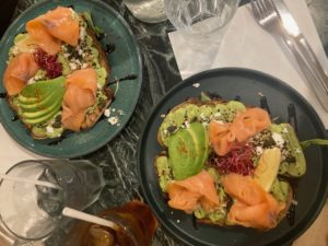Une image contenant un avocado toast avec du saumon fumé servi dans une assiette.